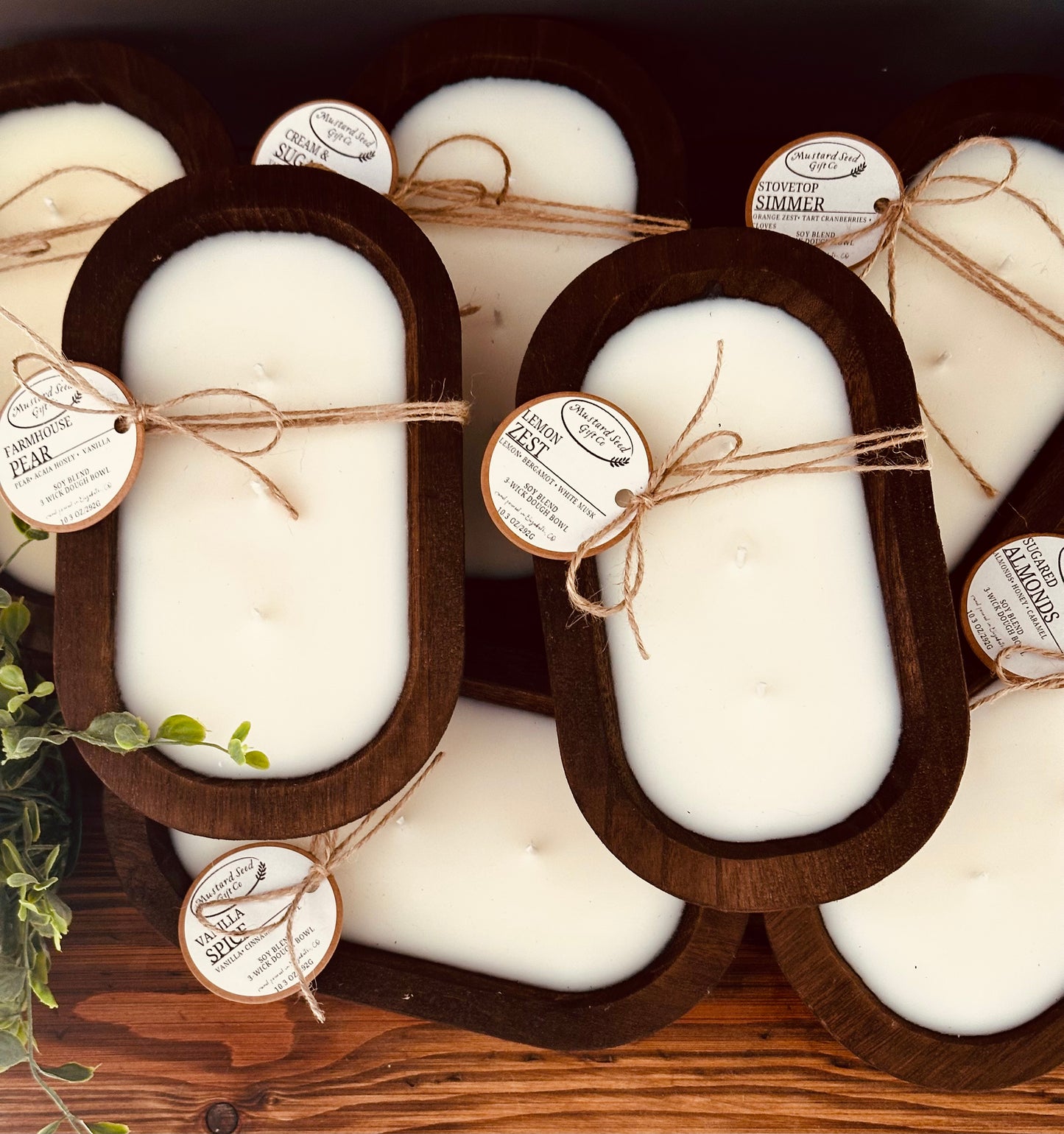 Set of white candles in wooden holders with labels on a wooden surface